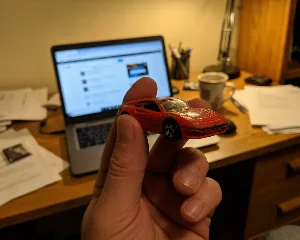 My hand holding a tiny toy sports car